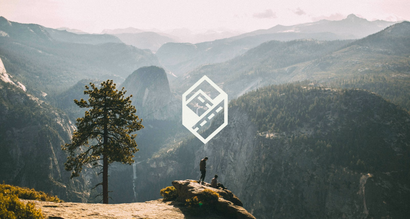 ExploreQuest hexagon logo set in the hazy sky on mountains background